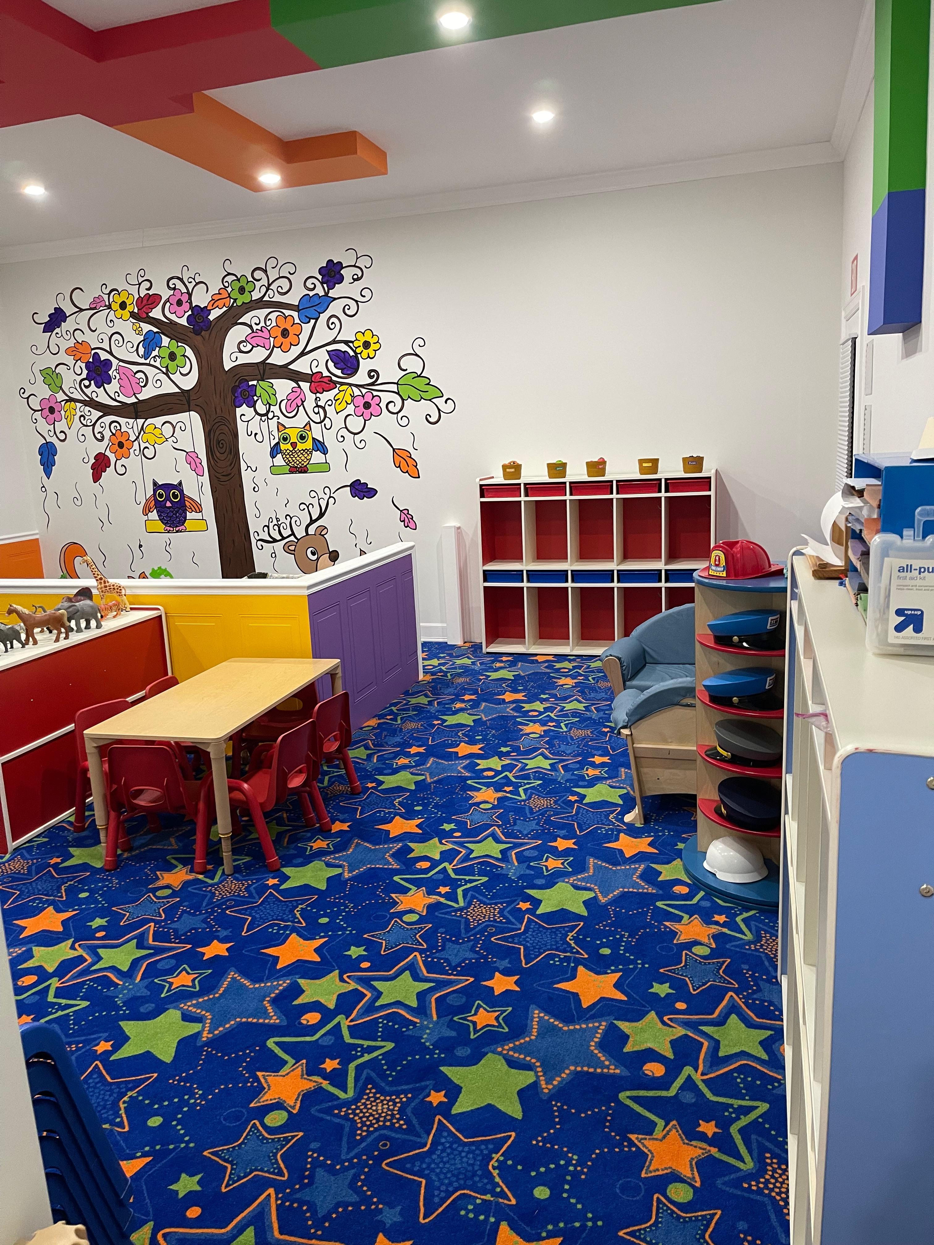 Colorful classroom with owl tree mural and star carpet