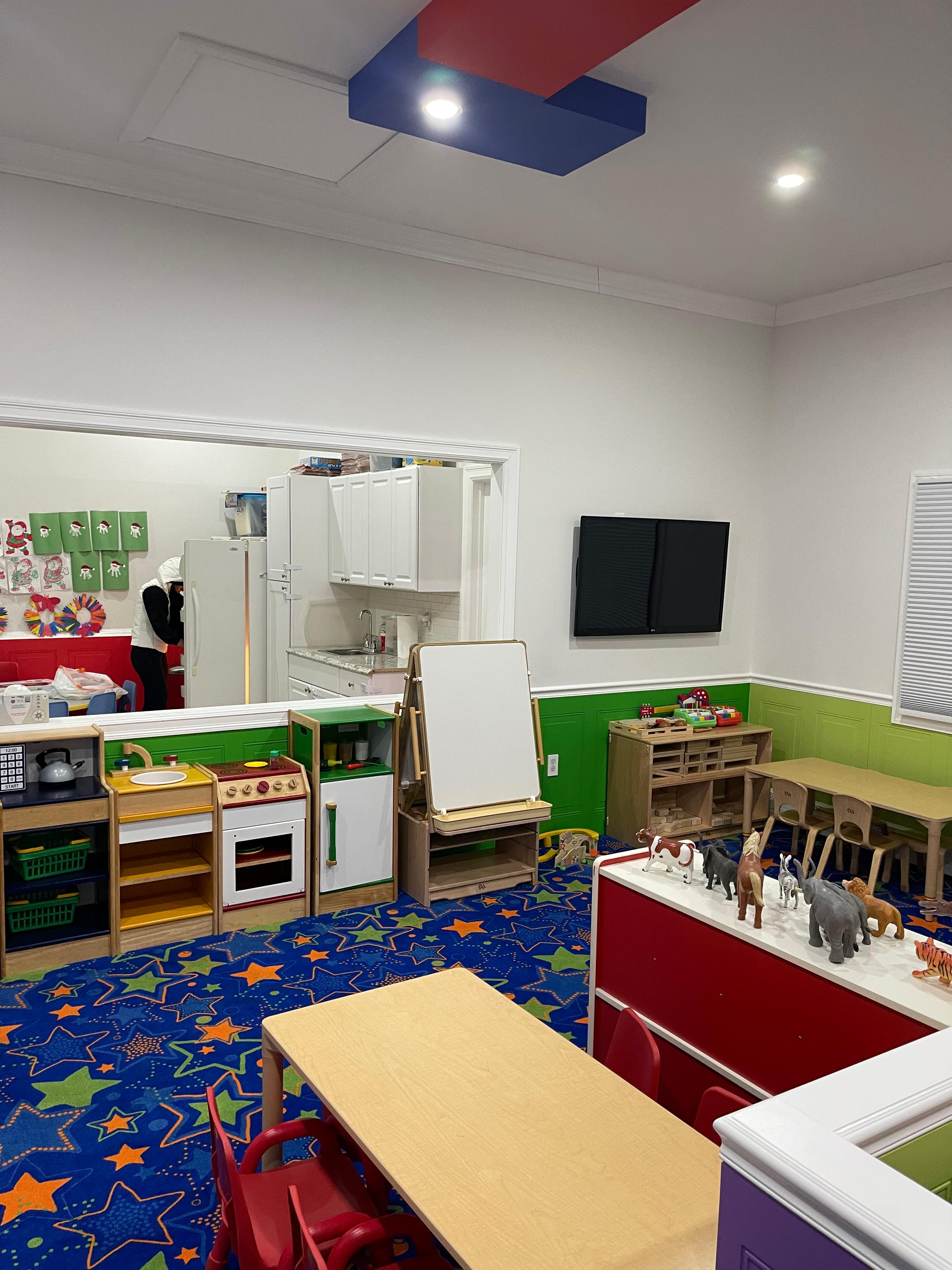 Classroom with play kitchen, easel and activity tables