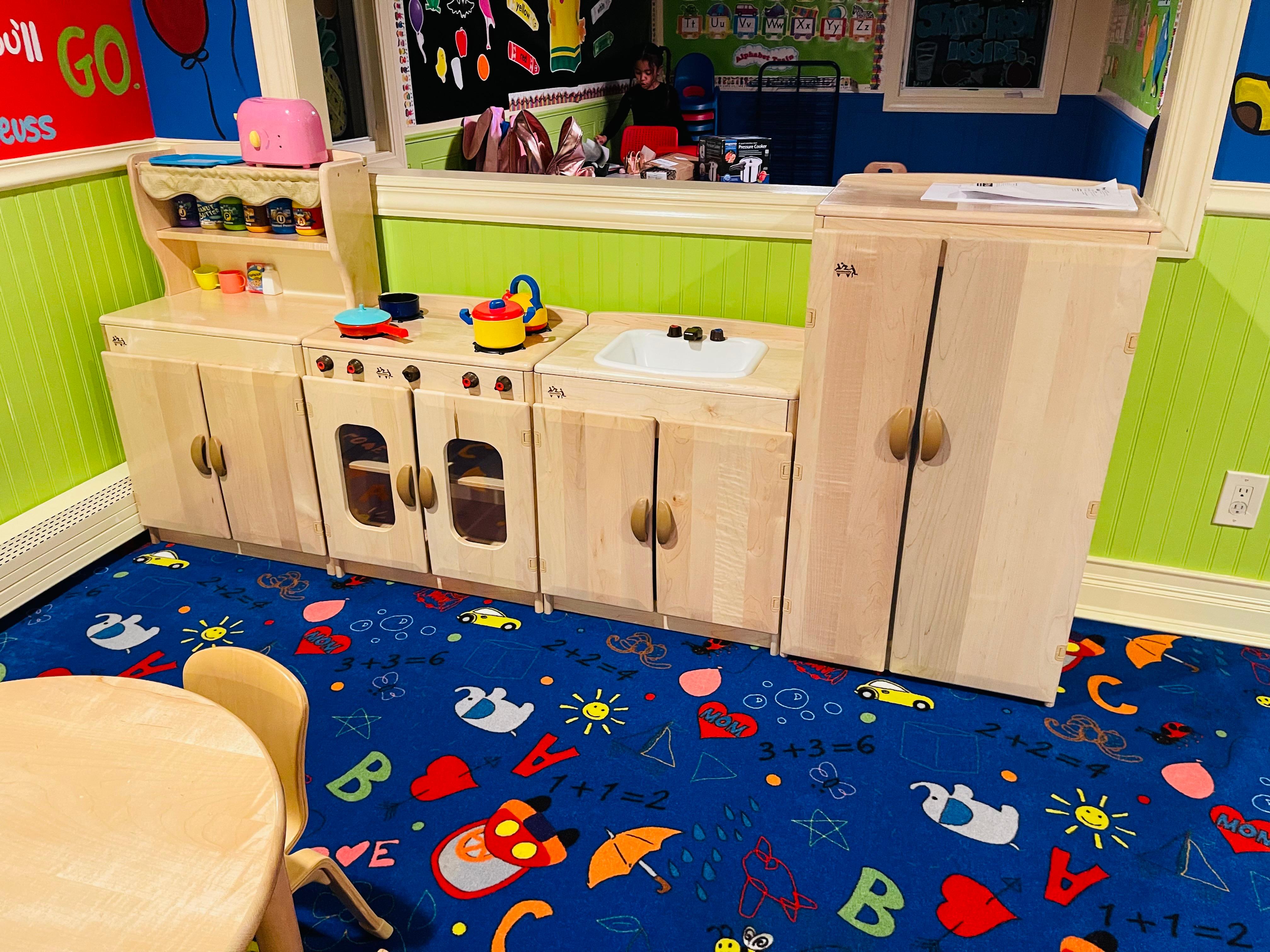 Wooden play kitchen set in green wainscoting room